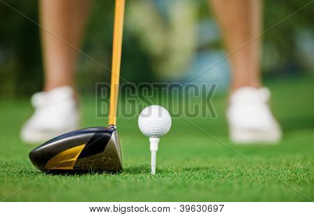 Golf ball and stick with golfer legs in background
