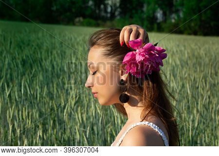 Beautiful Young Woman Model With Healthy Long Hair, Natural Makeup Holding Pink Peony Flower In Her 