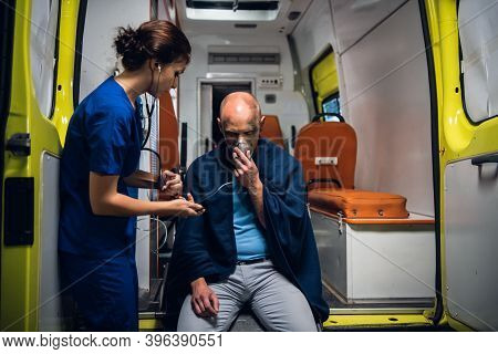 A Young Female Paramedic On Duty, Taking Care Of An Injured Man.