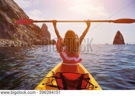 Young Attractive Brunette Woman In Red Swimsuit, Swimming On Kayak Around Volcanic Rocks, Like In Ic