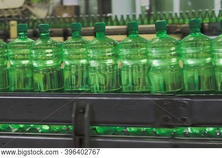 A Conveyer Belt With Green Plastic Bottles For Beverages. Perspective View. Concept Of Producing Cle