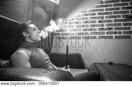 Sexy Man Blowing Clouds Of Smoke In The Hookah Bar.