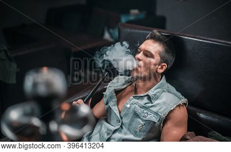 A Man Of European Appearance Exhales Smoke In The Hookah Bar.