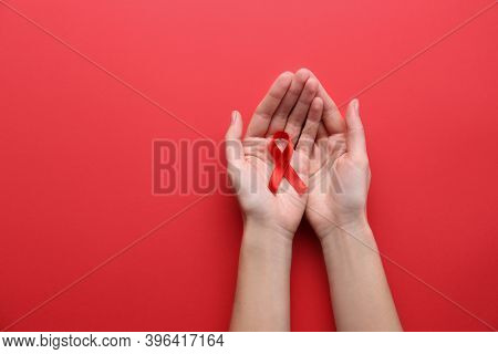 Woman Holding Red Awareness Ribbon On Color Background, Top View With Space For Text. World Aids Dis