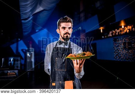 Whiskered Waiter Offers Visitors Dish On A Black Background.