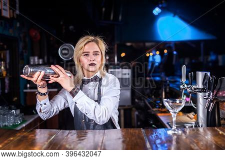 Focused Barmaid Demonstrates The Process Of Making A Cocktail While Standing Near The Bar Counter In