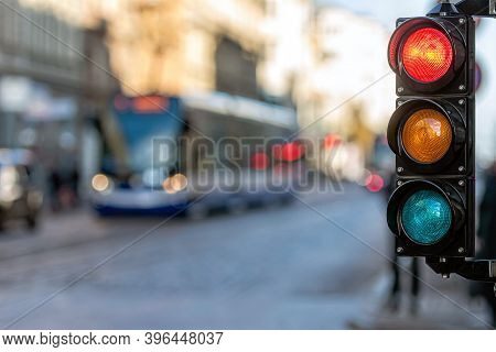 Close-up Of Small Traffic Semaphore With Red Light Against The Backdro Of The City Traffic