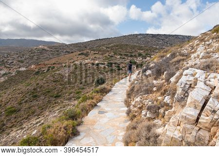 Woman On The Stone Mountain Path To Palaiokastro, Ruins Byzantine Castle On The Top Of Hill. Ios Isl