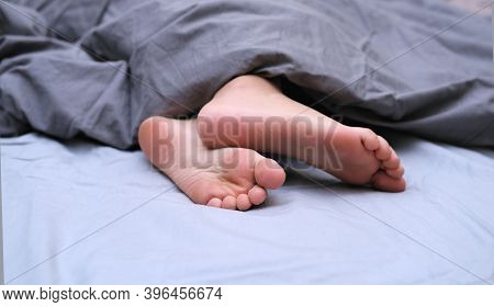 Girls Feet Covered With Bed Sheet. Crop View Of A Girl In The Bed Sleeping Tight. Melatonin, Cyrcadi