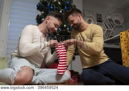 Same Sex Relationship. Family Bonding On The Christmas Eve. Young Gay Cuple Holding Christmas Stocki