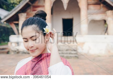 Portrait Of Happiness Asian Woman Wearing Laos Traditional Clothing And Using Plumeria Flower (dok C