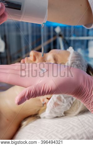 A Professional Beautician Applies Gel To A Gloved Hand.