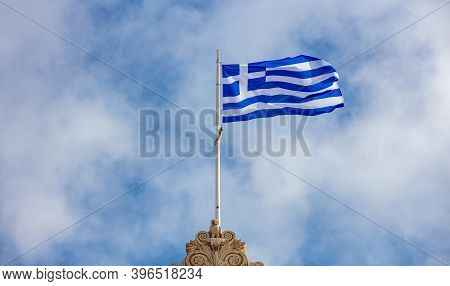 Greek Flag Waving On Pole Against Blue Cloudy Sky Background, Copy Space. Greece National Sign Symbo