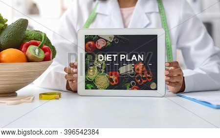 Black Dietologist Doctor Lady Demonstrating Digital Tablet With Opened Diet Nutrition Plan App With 