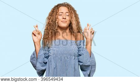 Beautiful caucasian teenager girl wearing summer dress gesturing finger crossed smiling with hope and eyes closed. luck and superstitious concept. 