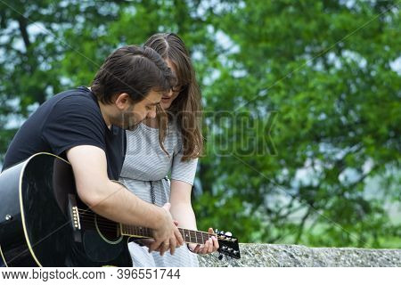 Older Brother Teaching His Younger Sister To Play Guitar In The Nature. Beautiful Moments Spent Toge
