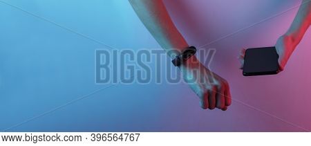 Female Hand With Smart Bracelet And Smartphone. Modern Gadgets. Creative Pop Art Pink Blue Neon Colo