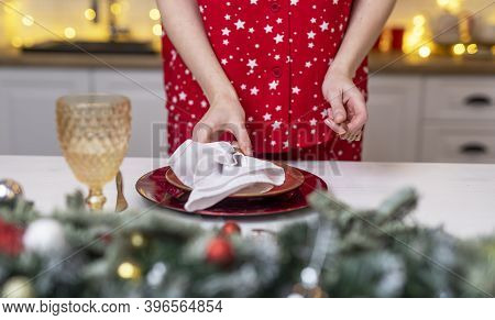 Female Hands Close Up Set The Table For Christmas, Decorating It With White Napkin, Plates And Wineg