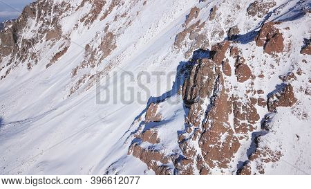 Huge Rocks Covered With Snow. Dangerous Terrain. High Mountains, Cliffs, And Large Rocks. Shadow Fro