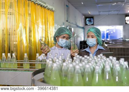 Quality Control Engineer  Work With Female Worker. Workers In The Factory Write Down Notes About Bot