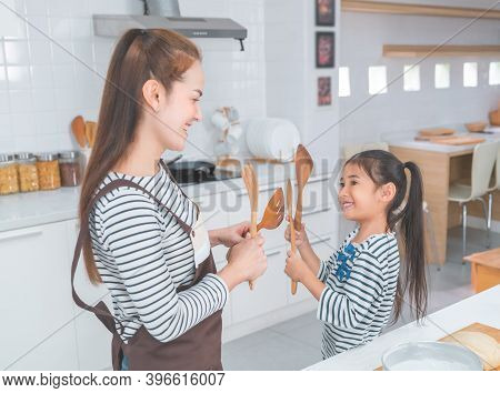 Mother And Daughter Holding Kitchen Equipments Getting Ready For Cooking Happy Time Together.