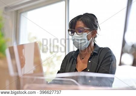 Office worker wearing surgical face mask in open space area