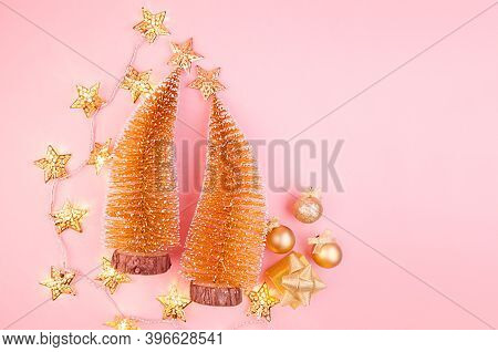 Christmas Decorations In Golden Color - Christmas Tree, Glowing Garland, Stars On Soft Light Pink Ba