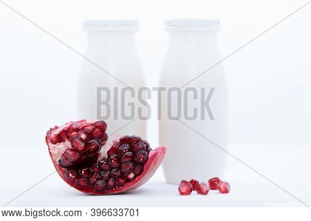 Natural Yogurt With Probiotics And Lactobacillus In Small Plastic Bottles And Red Ripe Pomegranate O