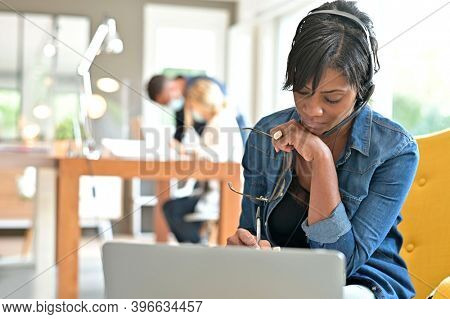 Businesswoman with headset working in open space coworking office