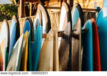 Set Of Different Color Surf Boards In A Stack By Ocean.bali.indonesia. Surf Boards On Sandy Beach Fo