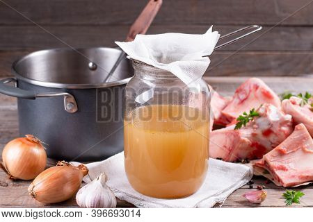 Passing The Bone Broth Through A Sieve And Through A Paper Napkin. Concentrated Bone Broth In A Glas