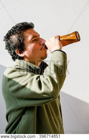 Drunk Man With An Alcohol Problem Standing Up Taking Beer From A Bottle