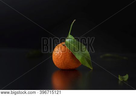 Fresh Orange Tangerine With Leavers Lies On A Black Table In The Black Background, Selective Focus. 