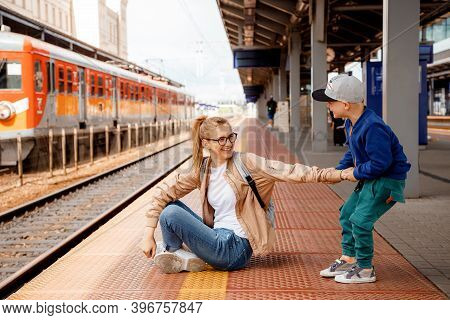 Woman With Son On The Platform Near The Train. Girl With A Preschool Boy Sitting At The Train Statio