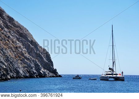 Sailboat Anchored Close To A Mountain Side Clif.