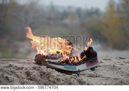 Burning Sports Sneakers Or Gym Shoes On Fire Stand On Sandy Beach Coast. Athlete Burned Out. Physica