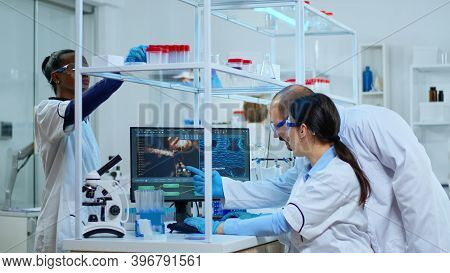 Team Of Microbiology Scientists Discussing About Virus Development In Modern Equpped Laboratory Usin