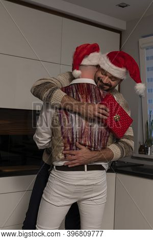 Young Homosexual Cuple, Men, Hugging And Exchanging Christmas Gifts. High Quality Photo