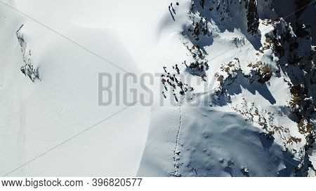 A Group Of Climbers Climb To The Top Of The Peak. Dangerous, Steep Slope. Avalanche-prone Area. Moun