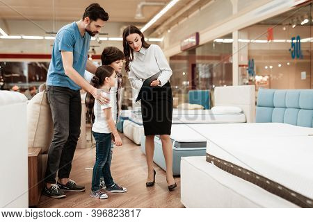 White Woman Consultant Demonstrates Orthopedic Mattress To Young Father With Children In Furniture S