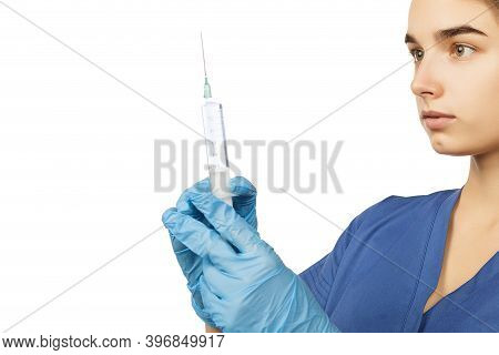 A Female Doctor In Blue Gloves And A Surgical Gown Holds A Syringe With A Drug In Her Hands In Front