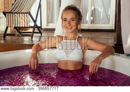 Woman Relaxing In Round Outdoor Bath With Tropical Flowers, Organic Skin Care, Luxury Spa Hotel Vale