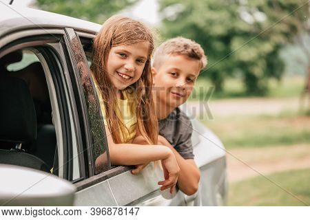 Two Cute Happy Kids Are Waving Their Hands Through Their Car Windows