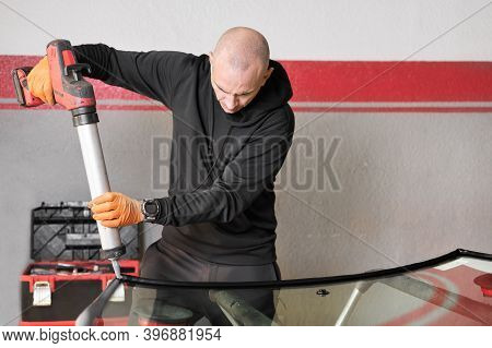 Glazier Applying Rubber Sealing To Windshield In Garage, Close Up. High Quality Photo