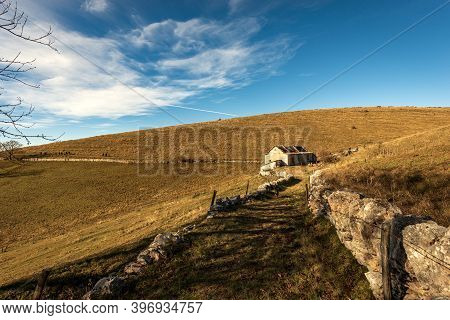 Trekking Path With A Farmhouse And Pastures In Autumn On Lessinia Plateau (altopiano Della Lessinia)