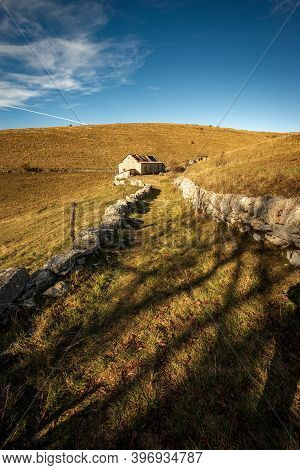 Trekking Path With A Farmhouse And Pastures In Autumn On Lessinia Plateau (altopiano Della Lessinia)