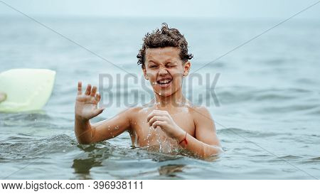Curly-haired Boy With A Happy Face Of A Sports Physique Bathes In The Sea