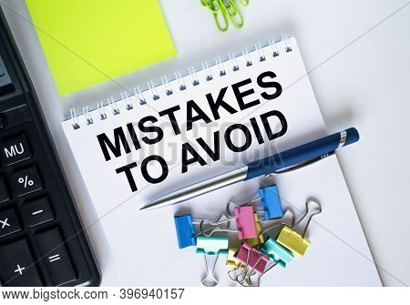 A Notepad With Text Mistakes To Avoid With Paper Clips And A Pen On It. Calculator And Yellow Sticke