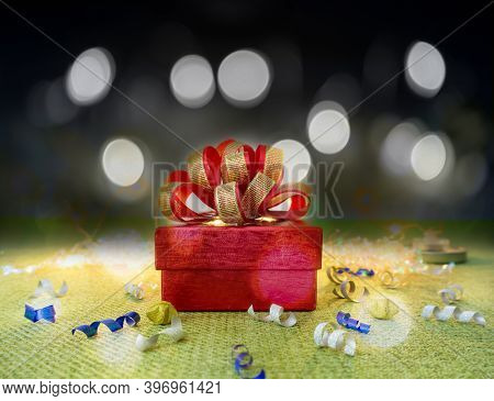 A Red Gift Box With Golden Ribbon For Celebrate Christmas And Happy New Year  On Green Fabric, Under
