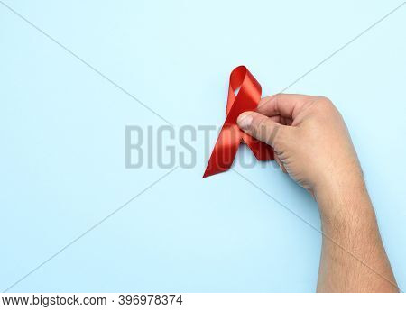 Man Hand Holds A Red Ribbon-symbol Of The Fight Against Disease Aids And Vasculitis, Close Up